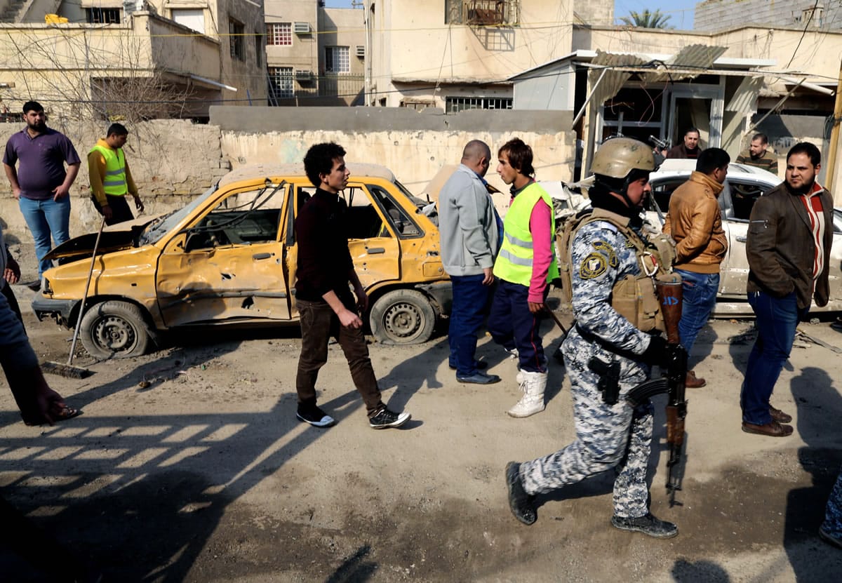 Civilians and security forces gather at the site of a car bomb attack near the Technology University in Sinaa Street in downtown Baghdad, Iraq, on Wednesday.