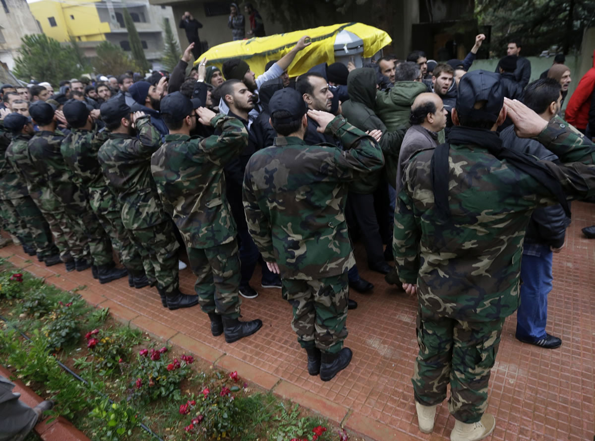 Hezbollah fighters salute as mourners pass by the coffin of Hassan al-Laqis, a senior commander for the Lebanese militant group Hezbollah, who was gunned down, during the funeral procession at his hometown in Baalbek city, east Lebanon, on Wednesday.