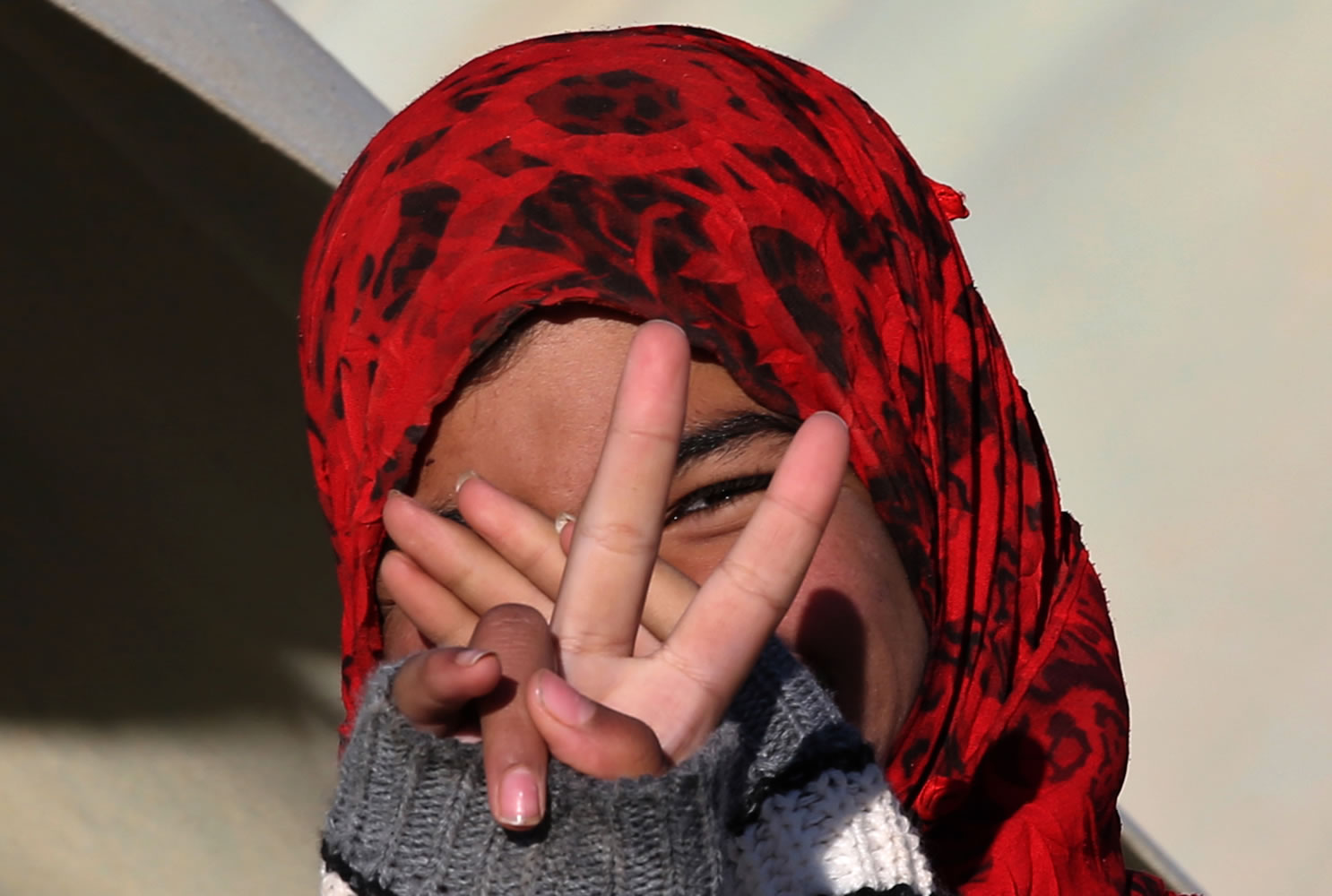 A Syrian girl flashes victory sign at a refugee camp in the eastern Lebanese border town of Arsal, Lebanon, on Friday