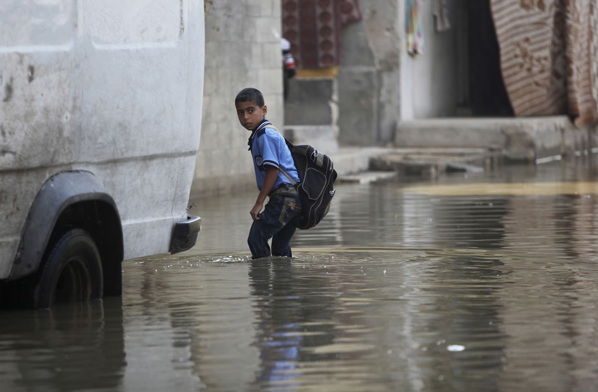 A Palestinian student wades through flooded waste water on his way back from scholl in Gaza City on Thursday.