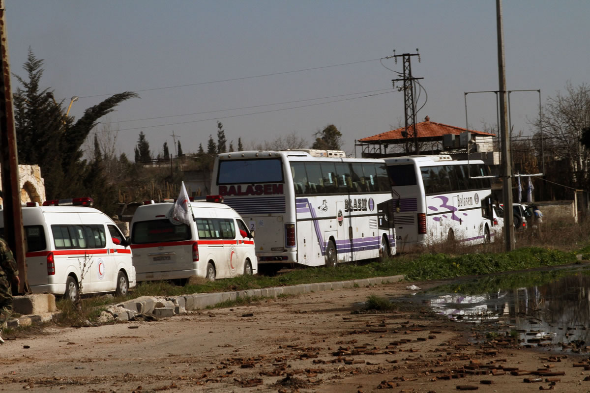 FILE - In this Friday, Feb. 7, 2014 file photo, Some Syrian people on two buses followed by the Syrian Arab Red Crescent's vehicles evacuate Syria's battleground city of Homs. A Syrian Red Crescent official says around 300 more people were evacuated Monday from besieged rebel-held neighborhoods of Syria's third-largest city, Homs.
