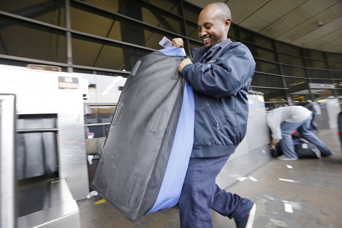 Skycap Biniyam Yehuala hefts a traveler's bag at Seattle-Tacoma International Airport in SeaTac.