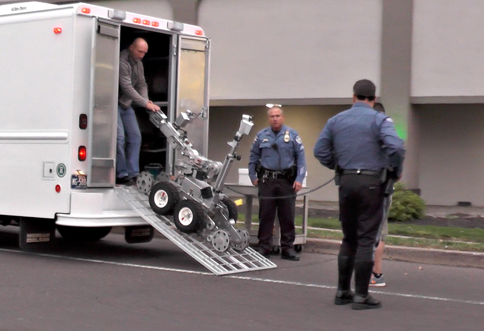 Police prepare to deploy a robot to inspect a room at the Knight Inn after reports of a shooting in Bensalem Township near Trevose, Pa., on Saturday. Police seeking someone on a parole violation stumbled upon another man and a woman who were wanted in a double homicide in North Carolina, and that man is dead after a standoff at the motel, authorities said Saturday.