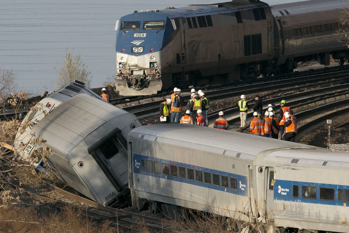 An Amtrak train, top, traveling on an unaffected track, passes a derailed Metro North commuter train Sunday in the Bronx borough of New York.