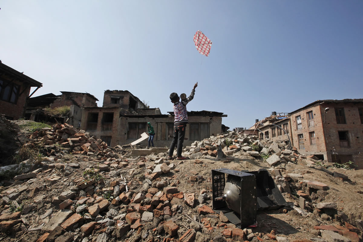 A Nepalese boy flies a kite Oct. 20 while standing on the debris of houses that collapsed in the April 25 earthquake in Bhaktapur, Nepal. Aid groups are warning of a crisis unfolding in Nepal as winter approaches, especially for the many of the estimated 400,000 Nepalis who live at elevations of 4,920 feet or higher. Some are still living in temporary shelters in camps across the country, though there is no official number. Their tents and huts built with tin sheets protected them from the monsoon rain but will be little match for the snow and below-freezing temperatures expected in mountain villages by the end of November.