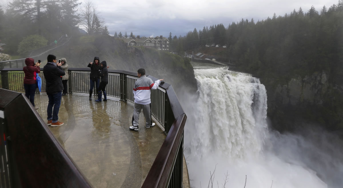 Visitors take photos as water pours over the 270-foot-high Snoqualmie Falls on Monday in Snoqualmie.