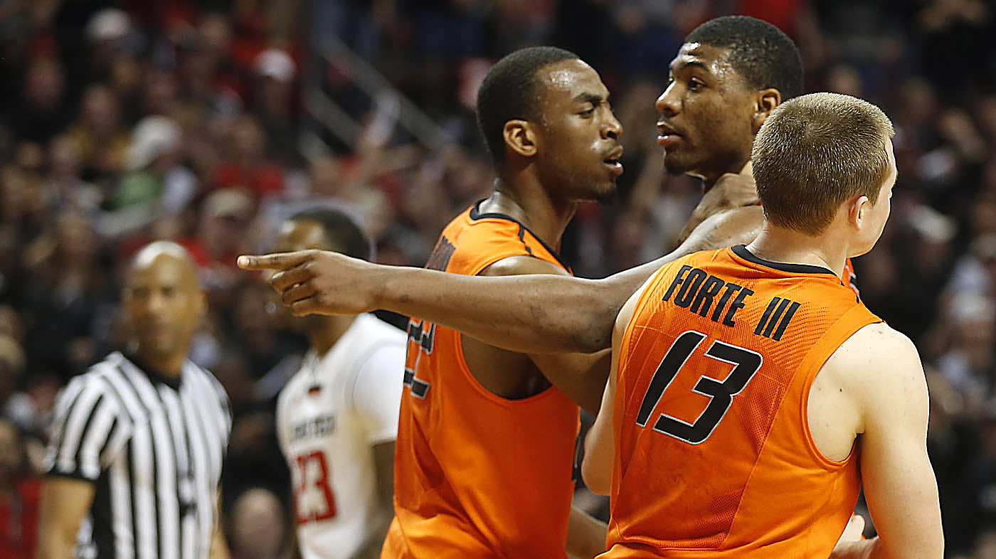 Oklahoma State's Markel Brown (22) and Phil Forte (13) hold Marcus Smart after Smart shoved a fan during their  game against Texas Tech in Lubbock, Texas, Saturday.