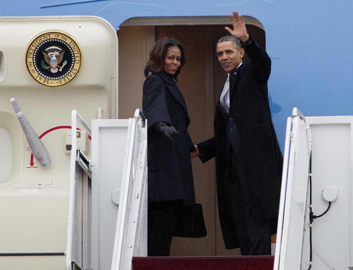 President Barack Obama, accompanied by first lady Michelle Obama, waves prior to boarding Air Force One at Andrews Air Force Base, Md., on Monday before traveling to South Africa for a memorial service in honor of Nelson Mandela.