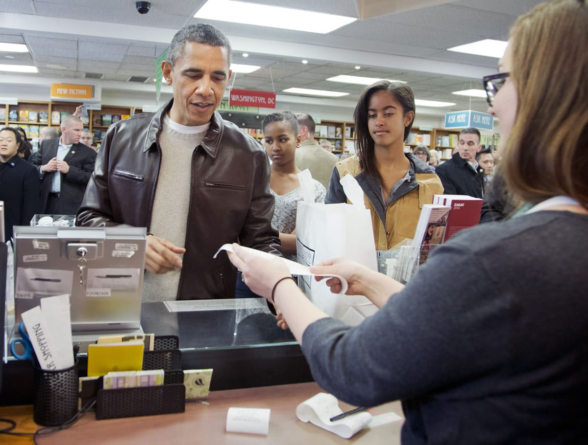President Barack Obama, with daughters Sasha, center, and Malia, pays for his purchase at Politics and Prose bookstore in northwest Washington on Saturday.