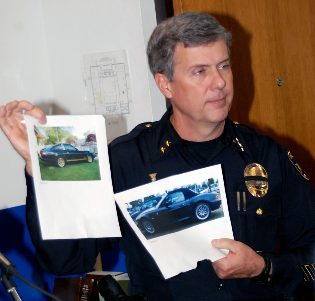 Police Chief Tim George holds up photos of sports cars similar to the description of one seen speeding away from the neighborhood where an improvised explosive device went off outside the Jackson County District Attorney's Office, during a news conference at City Hall in Medford, Ore., on Thursday. George said a witness was standing outside at around 4:30 a.m.