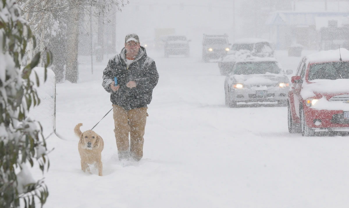 Roger Humble walks his dog Ty down South Main Road in Lebanon, Ore., on Thursday after droping his car off at Les Schwab to have snow tires mounted during the snowstorm.