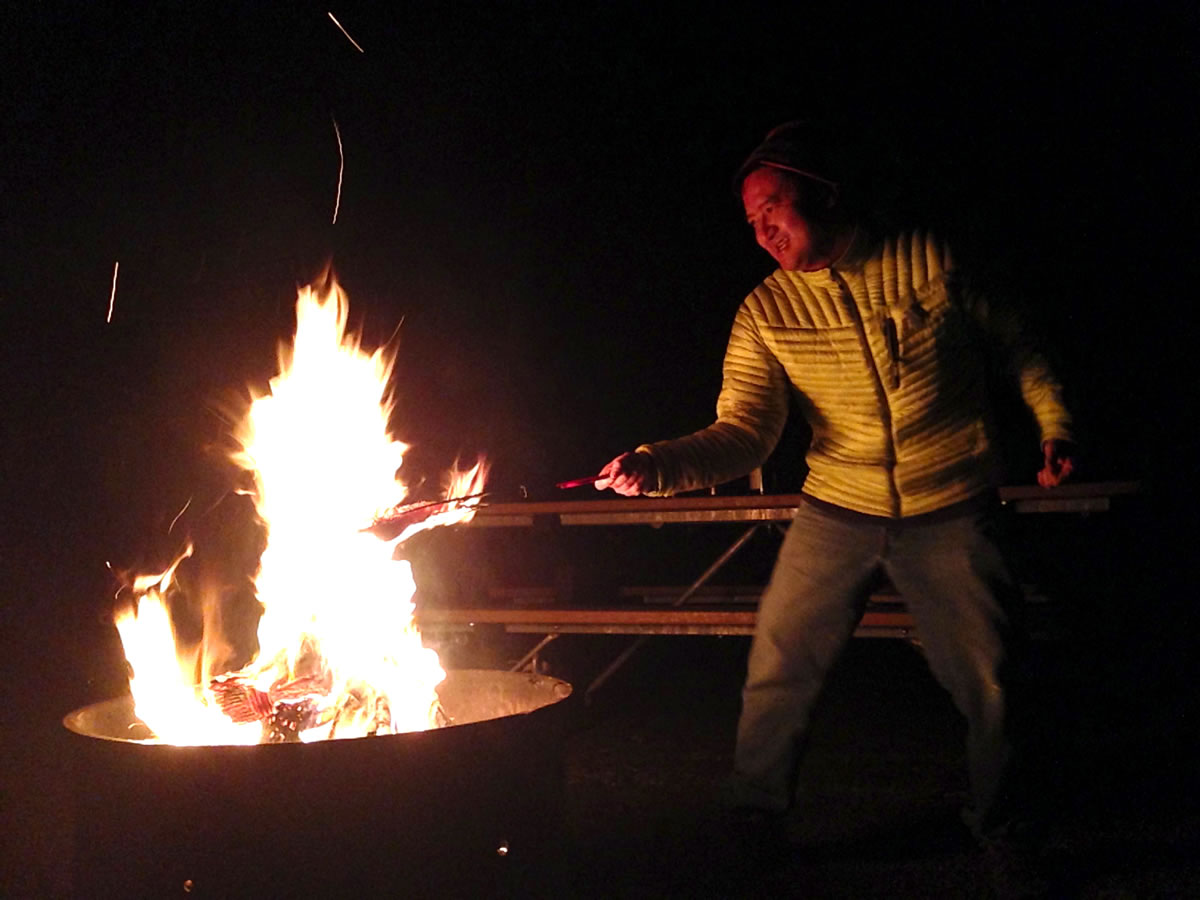 A man grills steelhead over an open fire in December outside the rental cabin at Ike Kinswa State Park.