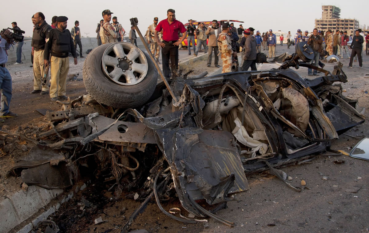 Pakistani investigators look at a vehicle destroyed by a bombing in Karachi, Pakistan, on Thursday.