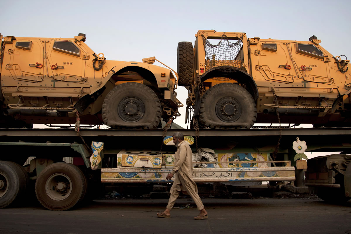 A man walks by a truck carrying NATO military vehicles at a terminal in Karachi, Pakistan, on Tuesday.