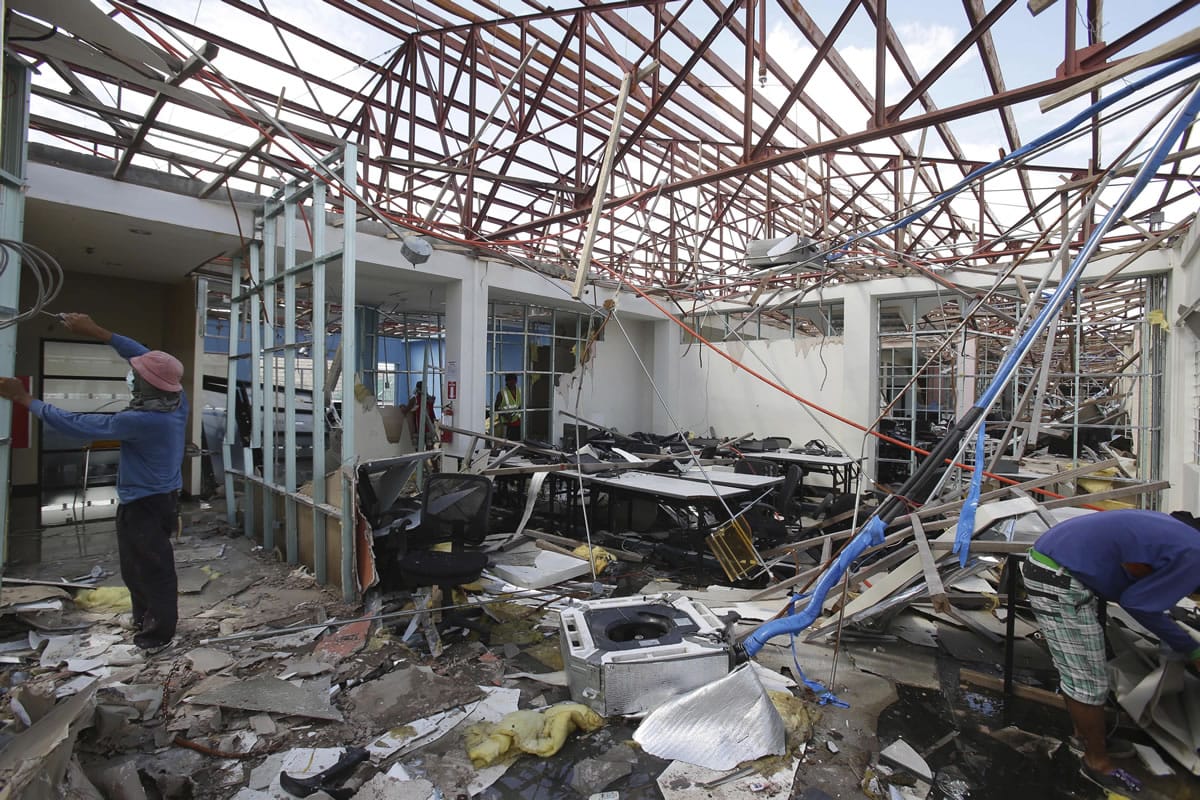 Workers clear debris at the damaged Expert Global Solutions call center in Palo, Leyte, central Philippines.
