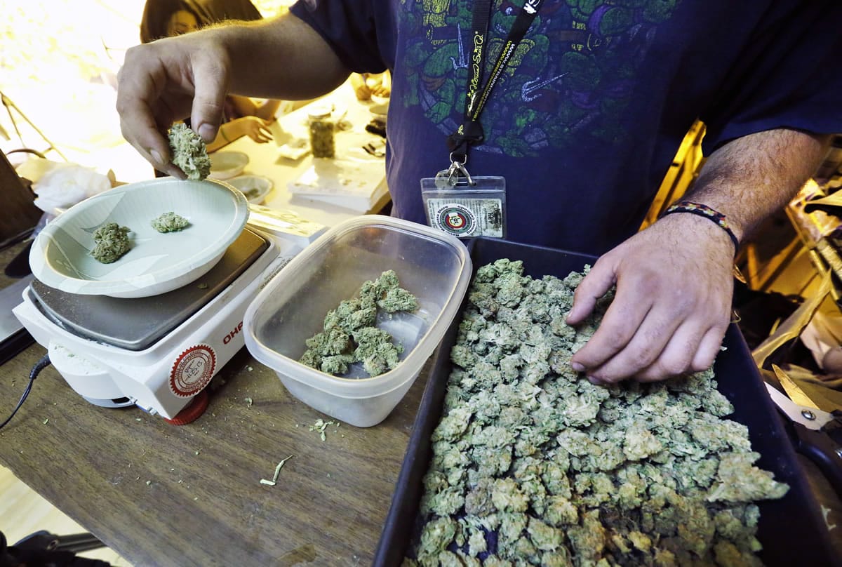 An employee weighs portions of retail marijuana to be packaged and sold at 3D Cannabis Center in Denver, Tuesday Dec. 31, 2013. Colorado is making final preparations for marijuana sales to begin Jan.