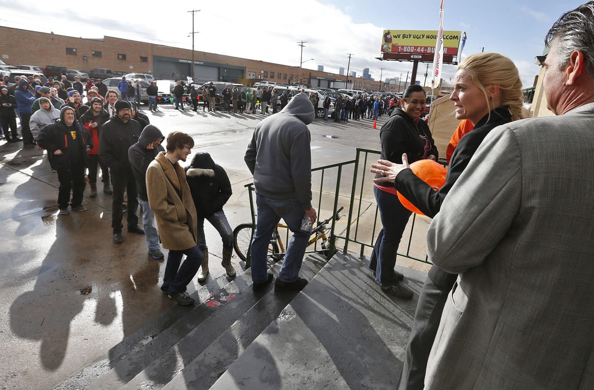 Store owner Toni Fox, second from right, greets customers standing in a line of several hundred people Wednesday morning shortly after the opening of her 3D Cannabis Center in Denver.