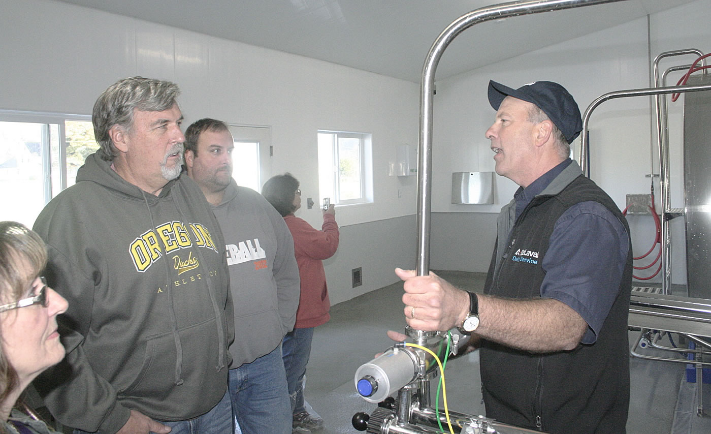 Mark Brown, right, a general manager for DeLaval Dairy Service, explains the automated systems to visitors at the Averill family dairy in Tillamook, Ore., Oct. 22, 2015. To many, this scenario represents the future of farming. As labor costs increase and the labor pool shrinks, farmers, such as the Averills, are turning to robotics and other technology to provide better care for their animals and increase efficiency.