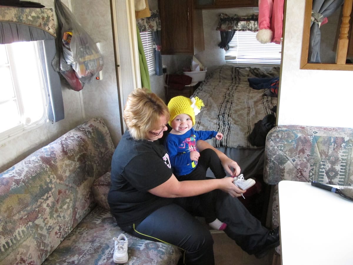 Kristin Dale puts shoes on her 18-month-old daughter, Aubrey, in the familyis trailer on Dec. 12 at Campbellsville, Ky.