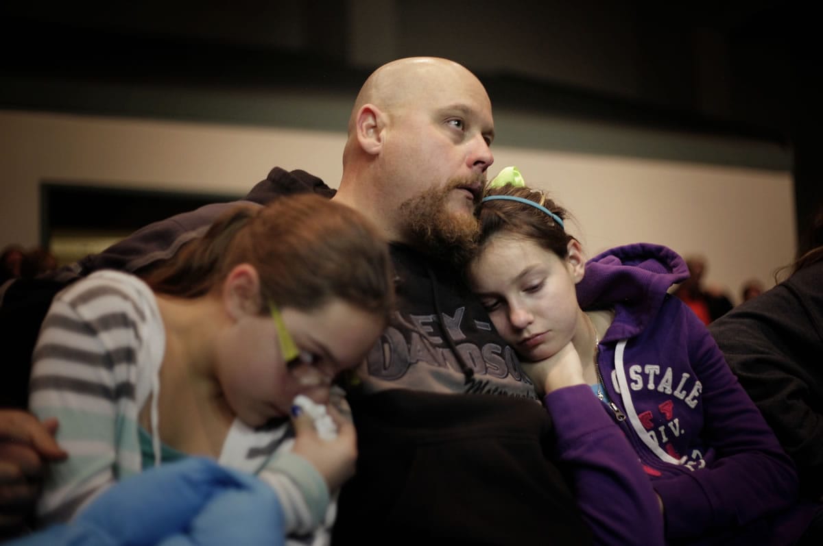 Troy Tucker, center of Roswell, N.M., holds his daughters Emily Tucker, left, age 10, and Hannah Tucker, right, age 12, during a community prayer vigil for the victims of the Berrendo Middle School shooting in Roswell, N.M., on Tuesday.