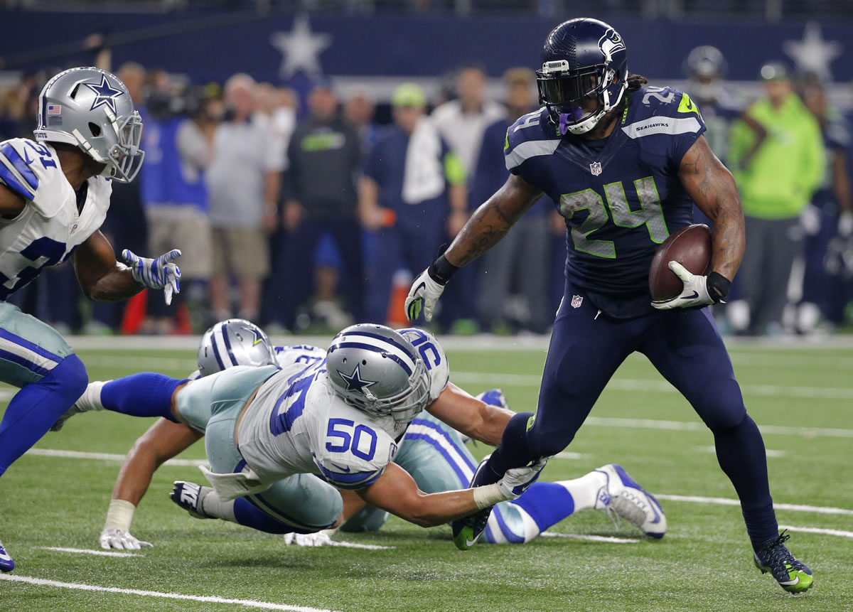 Seattle Seahawks running back Marshawn Lynch (24) breaks through a tackle-attempt by Dallas Cowboys' Sean Lee (50) as Cowboys Byron Jones, left, comes over to help on the running play in the second half of an NFL football game Sunday, Nov. 1, 2015, in Arlington, Texas.