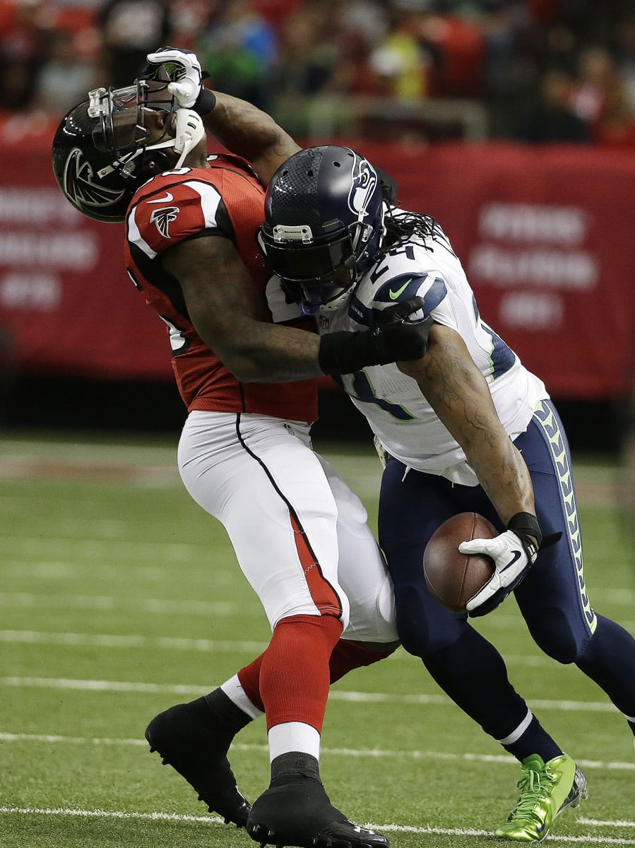 Seattle Seahawks running back Marshawn Lynch (24) holds off Atlanta Falcons strong safety William Moore (25) during the first half Sunday in Atlanta.
