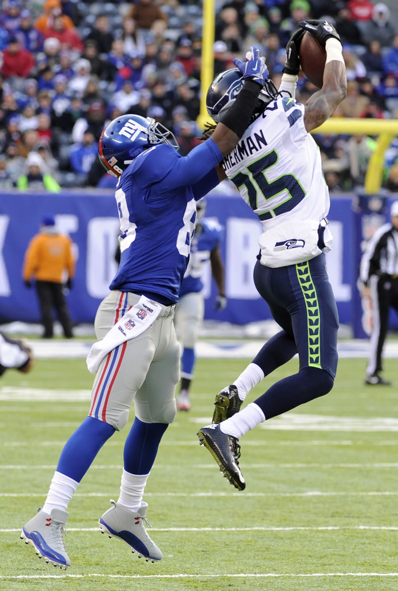 Seattle Seahawks cornerback Richard Sherman, right, intercepts a pass from New York Giants quarterback Eli Manning intended for wide receiver Hakeem Nicks, left, during the first half Sunday.