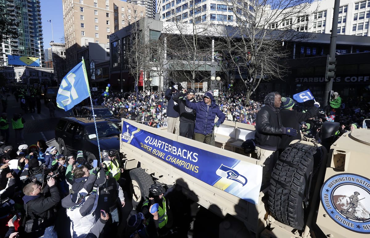Seattle Seahawks quarterback Russell Wilson, center, waves to fans during the Super Bowl champions parade on Wednesday, Feb. 5, 2014, in Seattle. The Seahawks defeated the Denver Broncos 43-8 in NFL football's Super Bowl XLVIII on Sunday. (AP Photo/Ted S.
