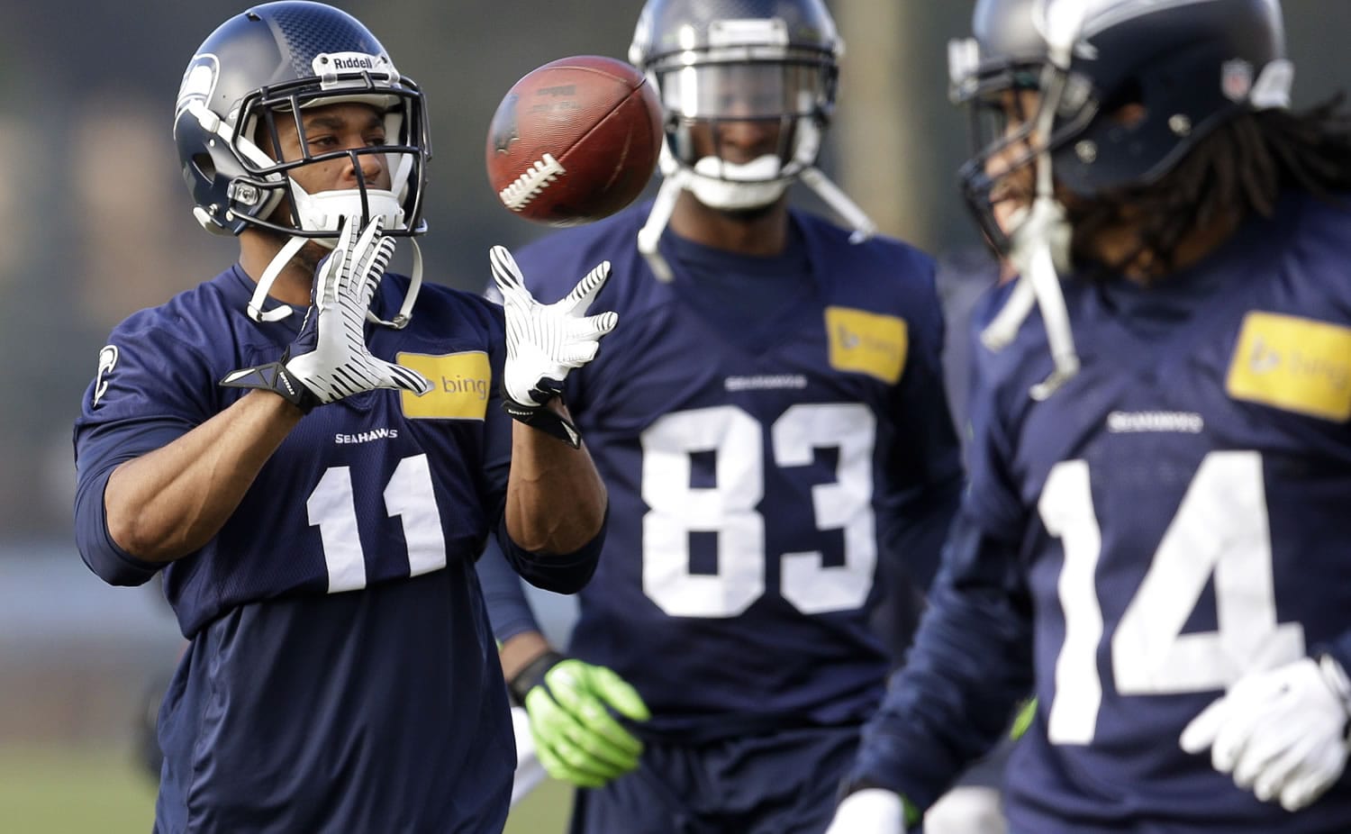 Seattle Seahawks wide receiver Percy Harvin (11) catches a ball tossed to him during warmups for Friday's practice. Looking on are wide receiver Ricardo Lockette (83) and practice squad wide receiver Arceto Clark (14). Seattle plays at home in a playoff game on Jan. 11. (AP Photo/Ted S.