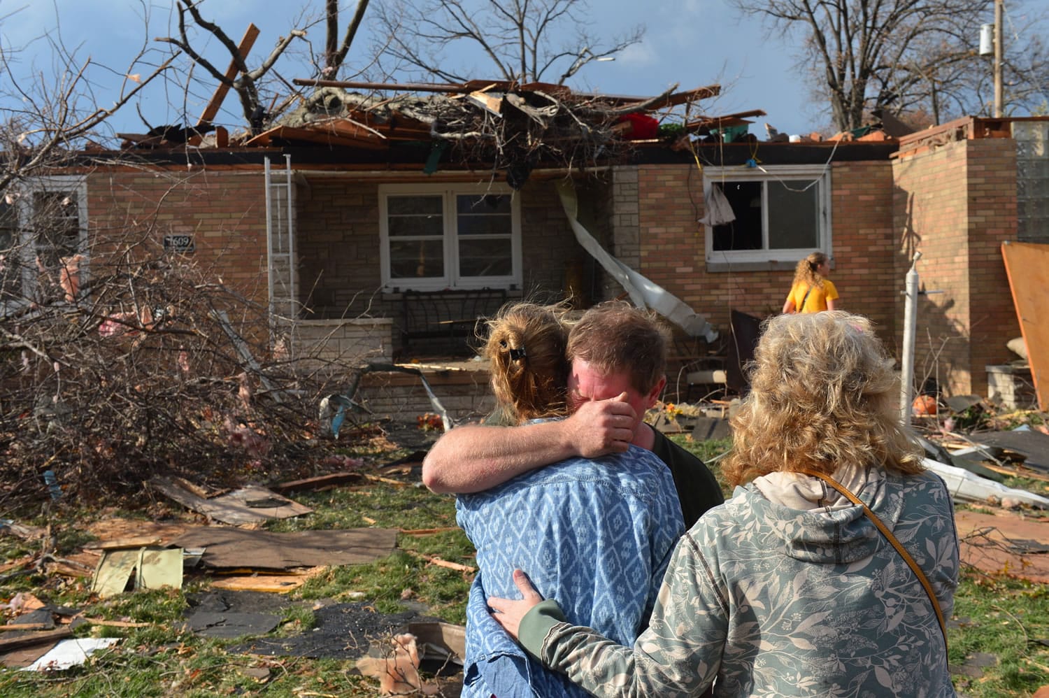 Ray Baughman embraces family shortly after his home was destroyed by a tornado that left a path of devastation through the north end of Pekin, Ill., on Sunday.