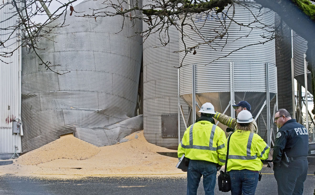Department of Labor and Industries officials meet with emergency personnel at the site of a collapsed grain silo Tuesday in Roy.