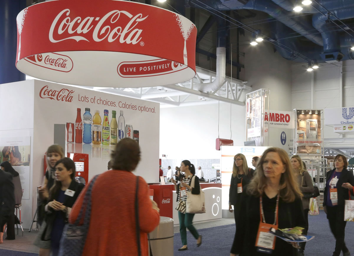 In this Oct. 21, 2013 photo, attendees at a conference for dietitians pass by a booth sponsored by Coca Cola, in Houston.