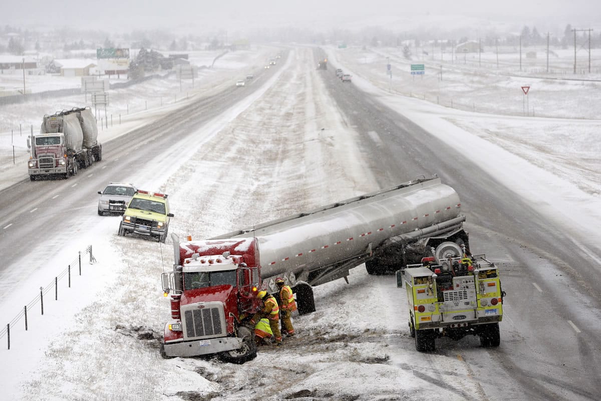 A tanker truck is tended to by firefighters after sliding off the snowy highway near mile marker 48 on Interstate 90 in Piedmont, S.D., on Tuesday afternoon.