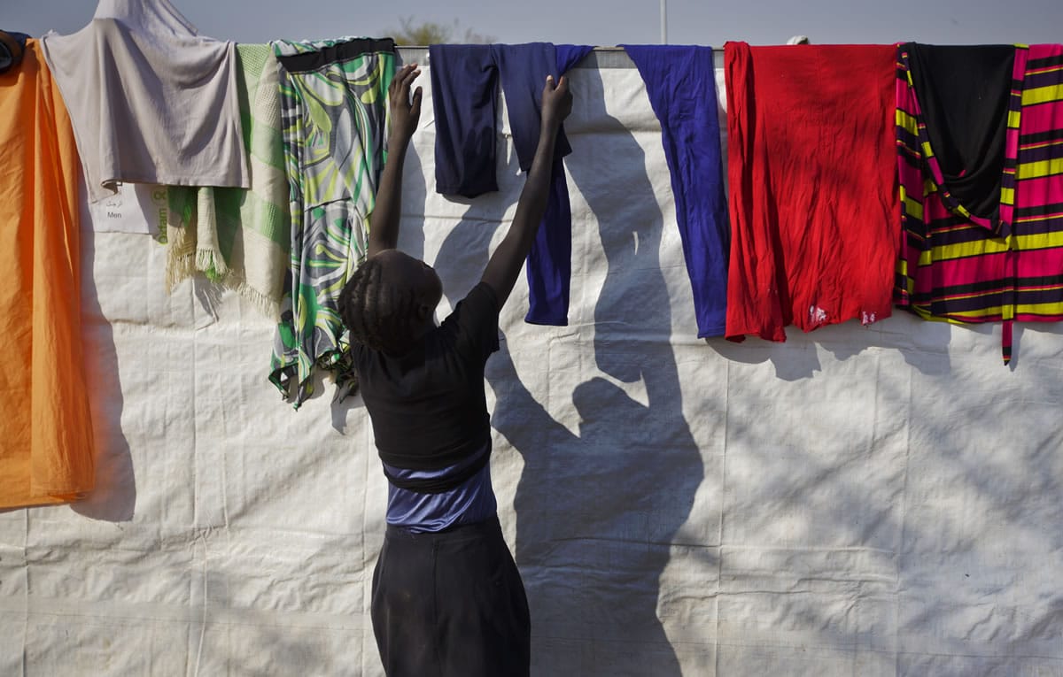 A displaced woman hangs up laundry to dry on the plastic sheeting wall of a latrine, at a United Nations compound which has become home to thousands of people displaced by the recent fighting, in the Jebel area on the outskirts of Juba, South Sudan, on Tuesday.