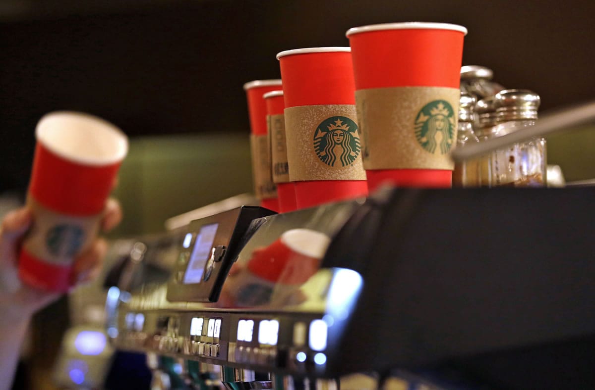 A barista reaches for a red paper cup as more, with cardboard liners already attached, line the top of an espresso machine at a Starbucks coffee shop in the Pike Place Market on Nov. 10 in Seattle.