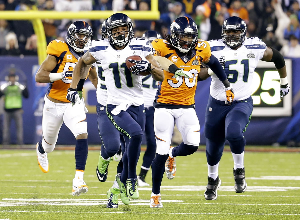 Seattle Seahawks' Percy Harvin (11) runs from Denver Broncos' David Bruton (30) while returning a kickoff 87-yards for a touchdown during to start the second half. (AP Photo/Ted S.