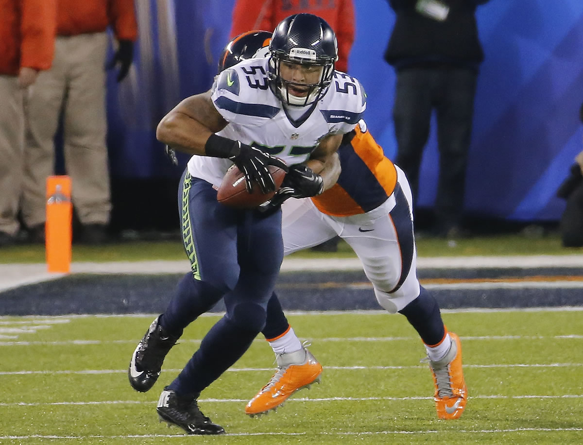 Seattle Seahawks' Malcolm Smith (53) picks up a fumble by Denver Broncos wide receiver Demaryius Thomas as Denver Broncos' Julius Thomas (80) grabs him during the second half. Smith was named Super Bowl MVP.