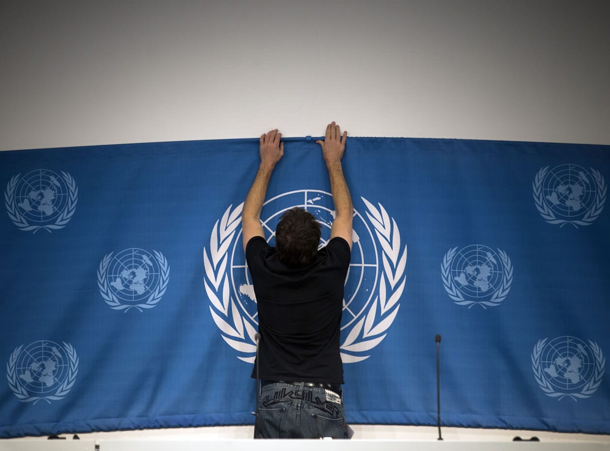 A worker sets up a United Nations banner at the media center in preparations for the start of this week's Syria peace talks in Montreux and Geneva in Montreux, Switzerland, on Tuesday.