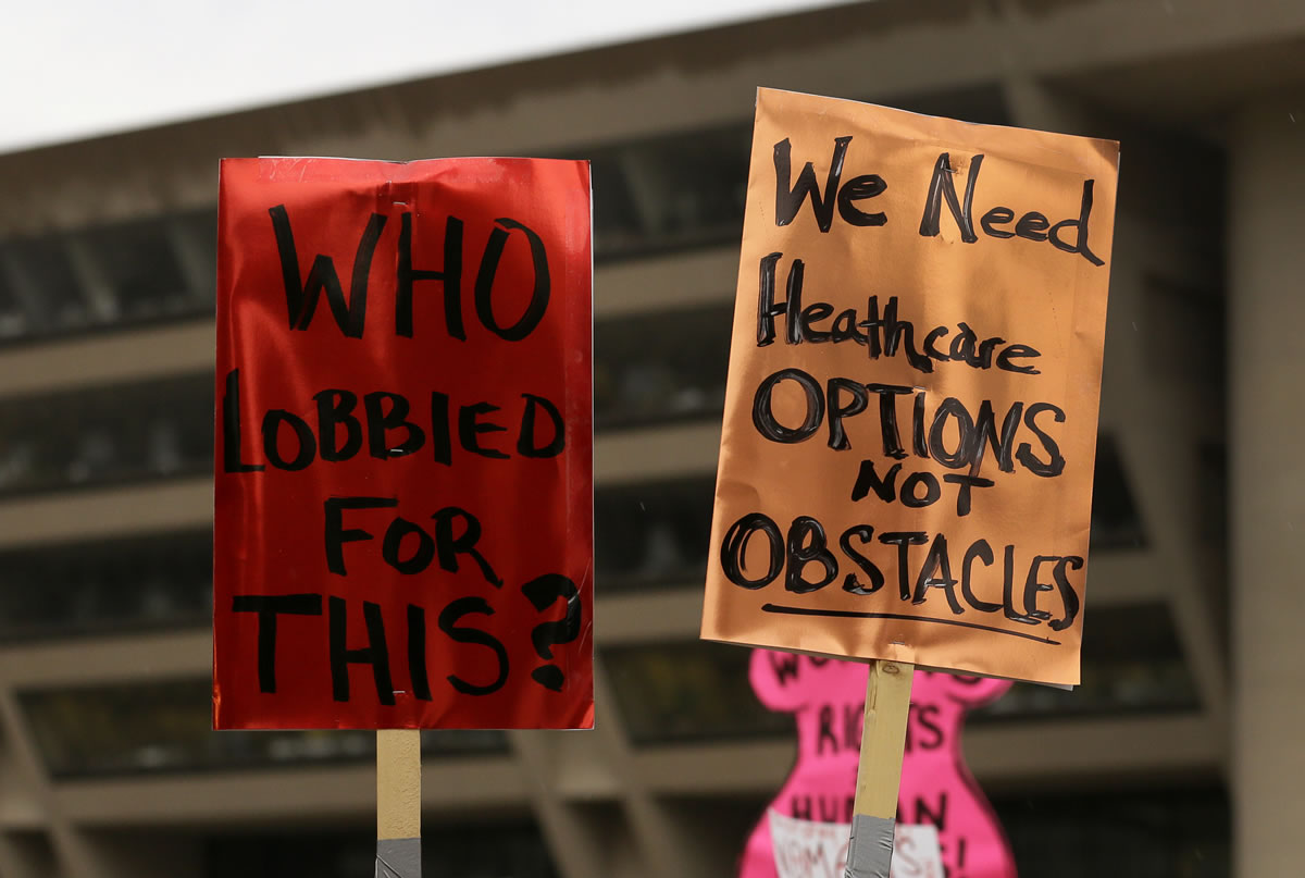 Two signs that read &quot;Who Lobbied For This?&quot; and &quot;We Need Healthcare Options, Not Obstacles&quot; are held by attendees of a rally in front of Dallas city hall where a group of nearly 200 gathered to protest the approval of sweeping new restrictions on abortion in Texas. A U.S.