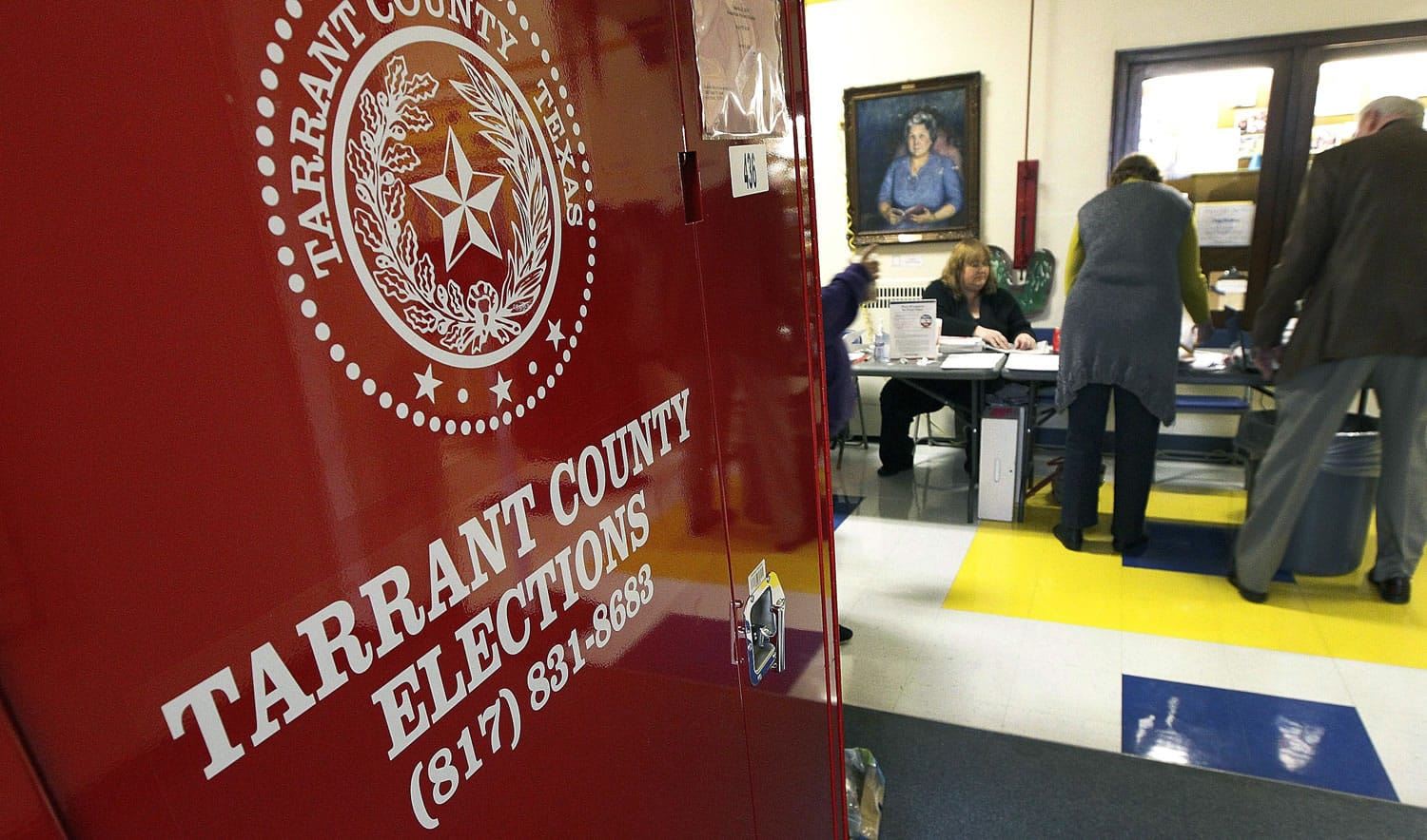Election officials work the voting area at North Hi Mount Elementary School as children make their way to class Tuesday in Fort Worth, Texas.