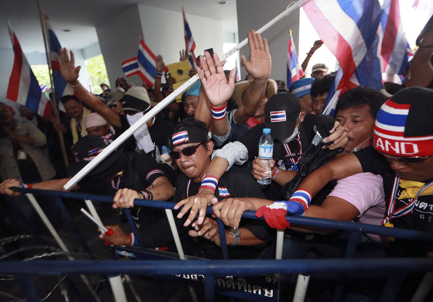 Anti-government protesters try to remove a police barricade during a rally in front of the Department of Special Investigation on Saturday in Bangkok, Thailand.
