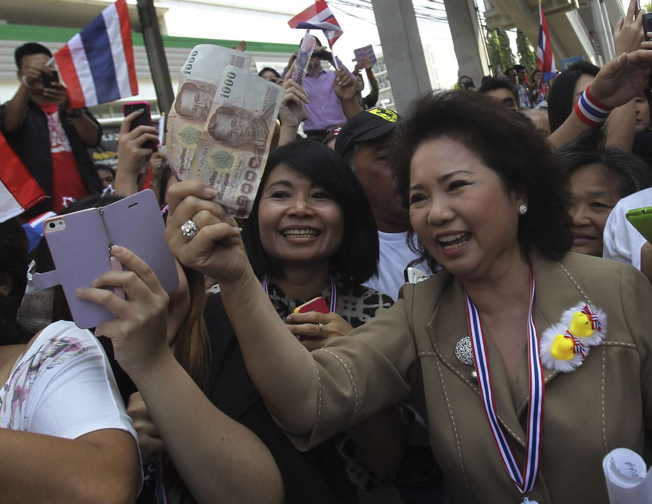 Supporters of anti-government protest raise bank notes to donate to Thai anti-government protest leader Suthep Thaugsuban during a protest march Tuesday in Bangkok, Thailand.