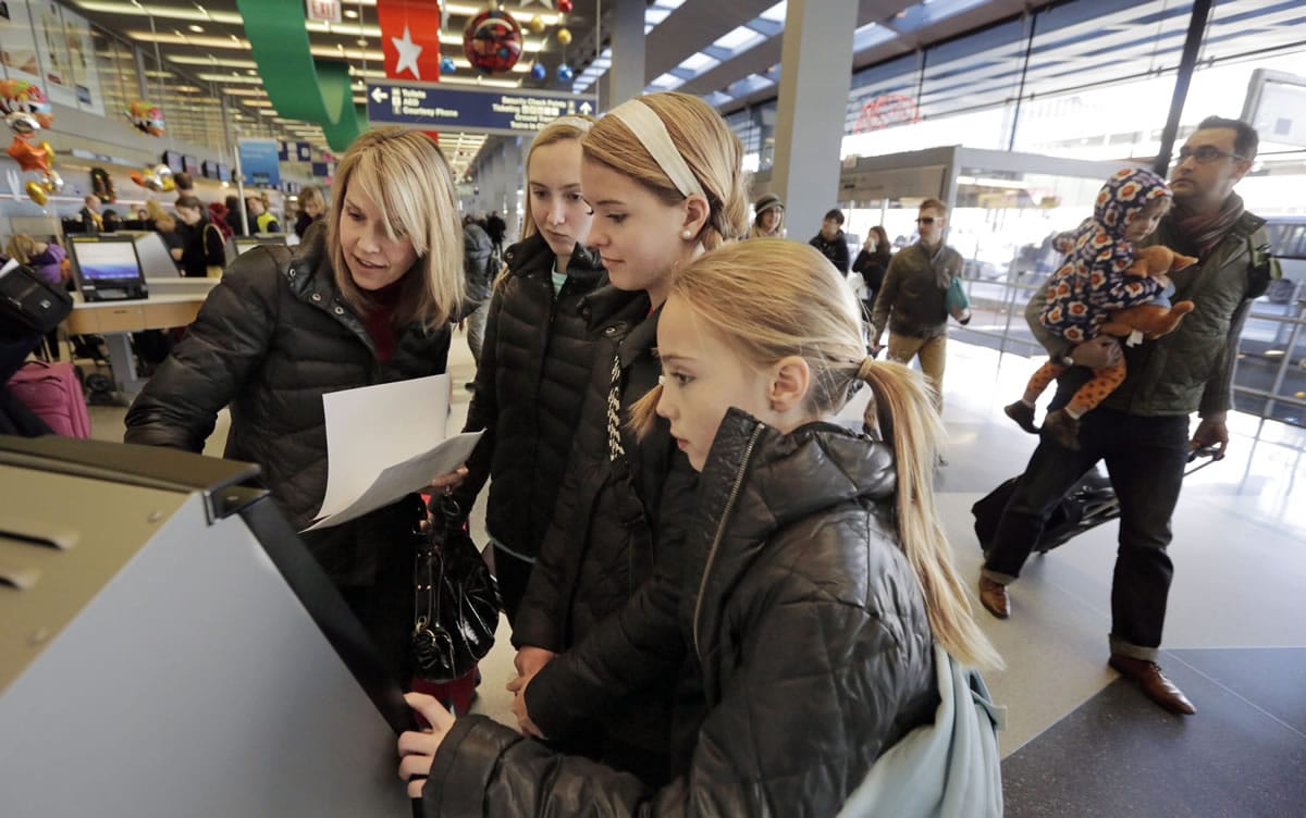 From left, Cindy Lawrence, and her daughters, Katie, Jenna and Sara, attempt to print boarding passes for their flight to Michigan on Wednesday at O'Hare International airport in Chicago.