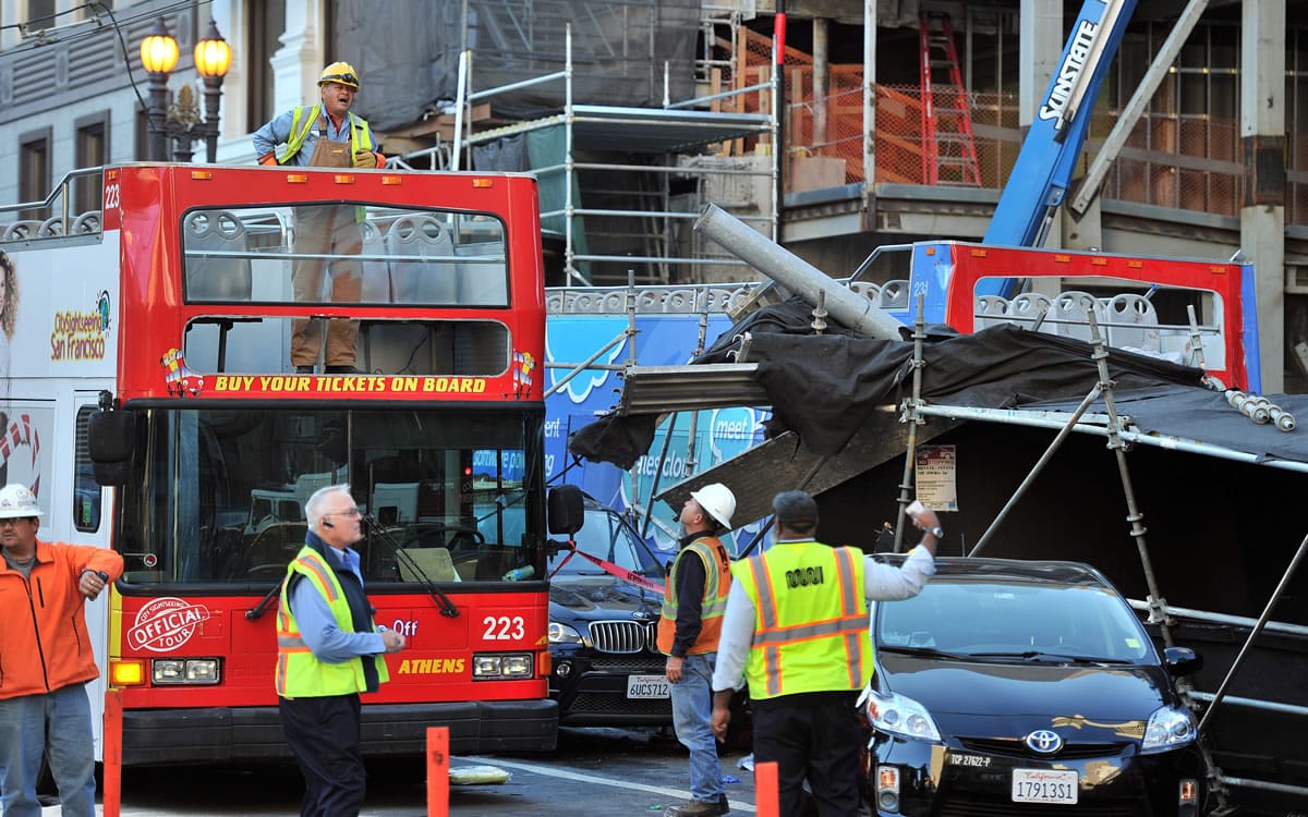 MUNI workers assess the scene of a crash near Union Square on Friday in San Francisco, where a double-decker tour bus crashed into vehicles and pedestrians.