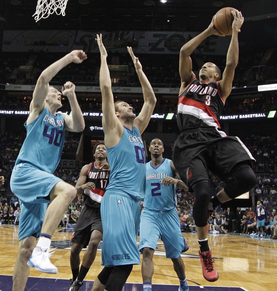 Portland Trail Blazers' C.J. McCollum (3) shoots over Charlotte Hornets' Spencer Hawes (00) and Cody Zeller (40) during the first half of an NBA basketball game in Charlotte, N.C., Sunday, Nov. 15, 2015.