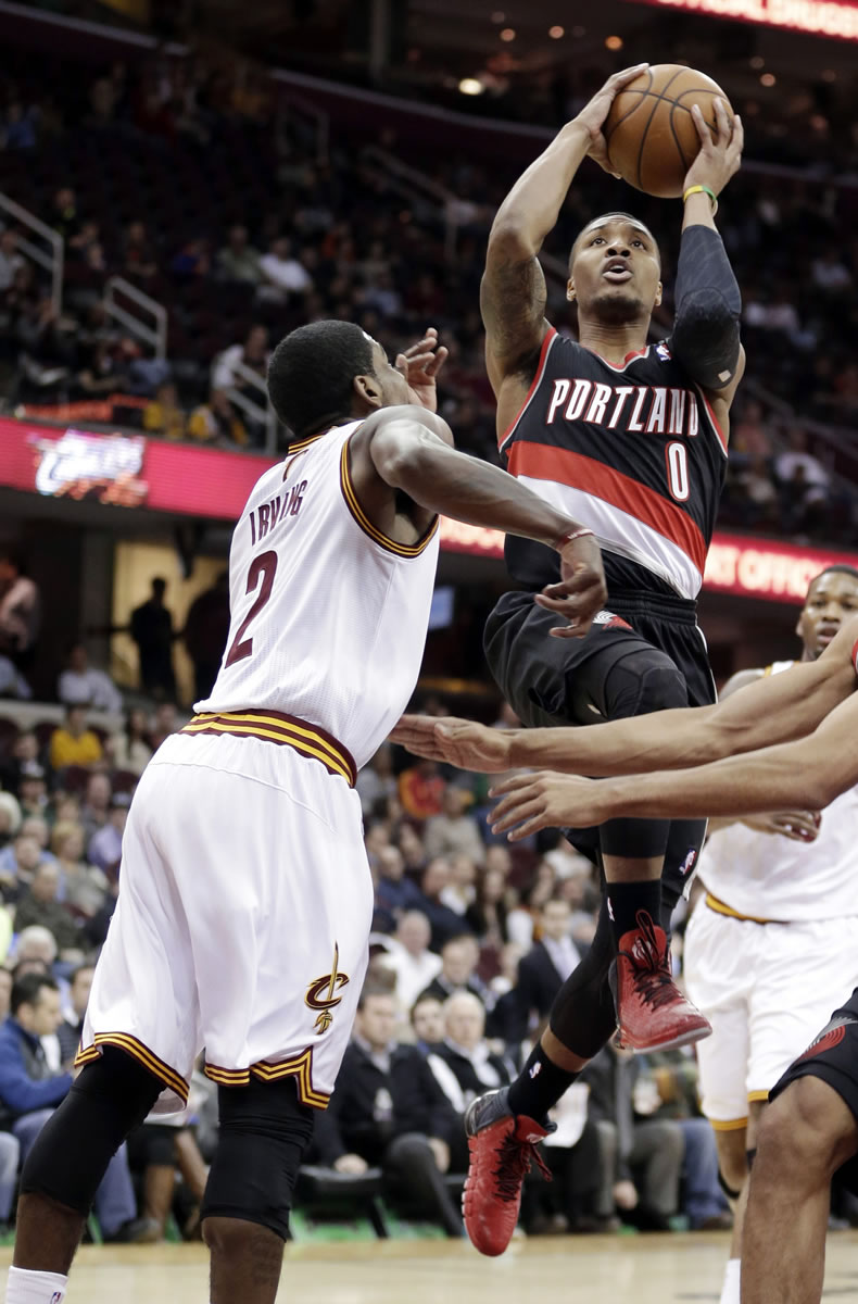 Portland Trail Blazers' Damian Lillard (0) jumps to the basket against Cleveland Cavaliers' Kyrie Irving (2) during the first quarter of an NBA basketball game Tuesday, Dec. 17, 2013, in Cleveland.