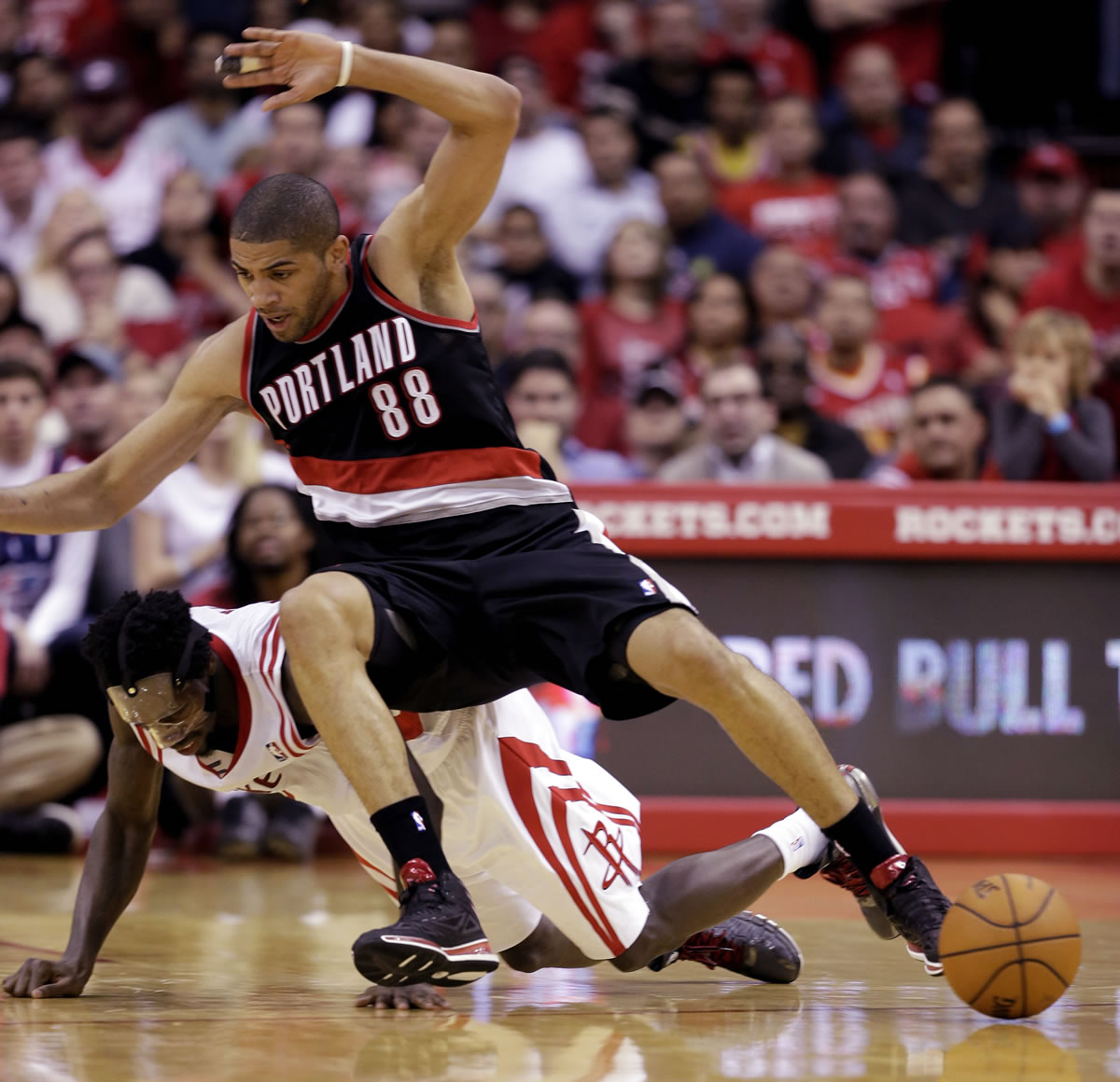 Portland's Nicolas Batum falls on Houston's Patrick Beverley while chasing a loose ball during the fourth quarter Sunday.