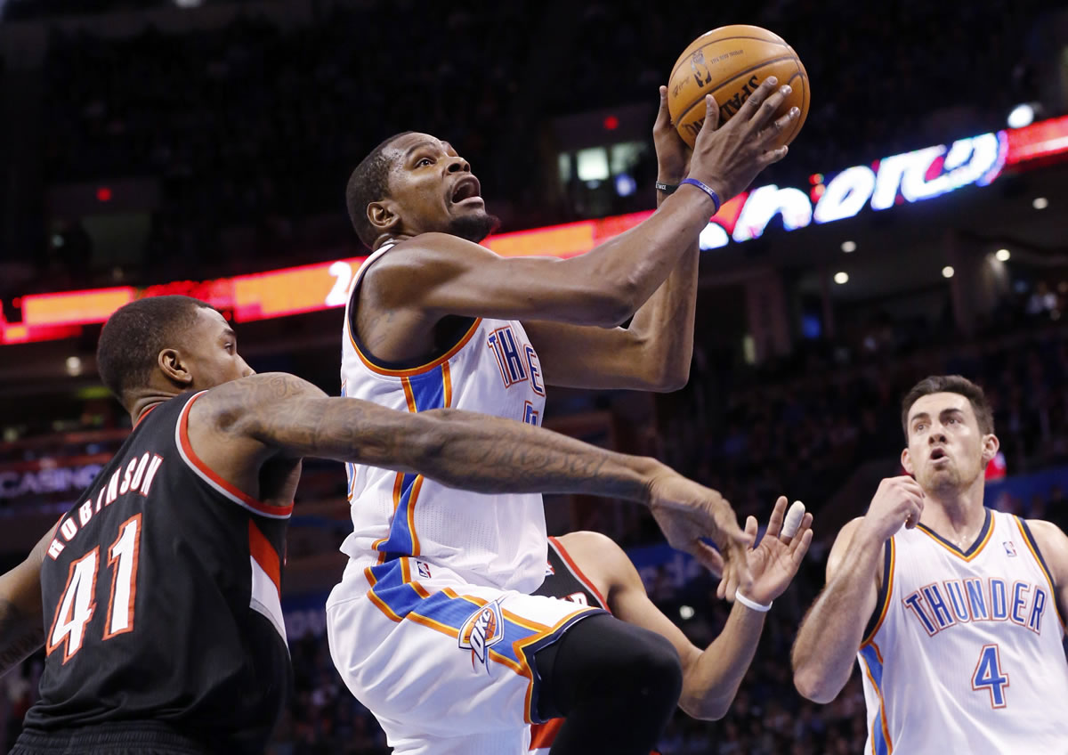 Oklahoma City Thunder forward Kevin Durant, center, shoots in front of Portland Trail Blazers forward Thomas Robinson (41) and teammate Nick Collison (4) in the third quarter of an NBA basketball game in Oklahoma City, Tuesday, Jan. 21, 2014. Oklahoma City won 105-97.