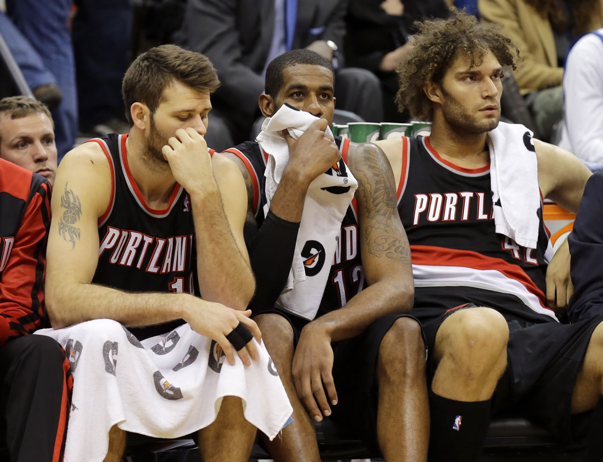 Portland Trail Blazers' Joel Freeland, left, LaMarcus Aldridge, center, and Robin Lopez, right, sit on the bench during the final minutes of their team's 120-109 loss to the Minnesota Timberwolves on Wednesday.