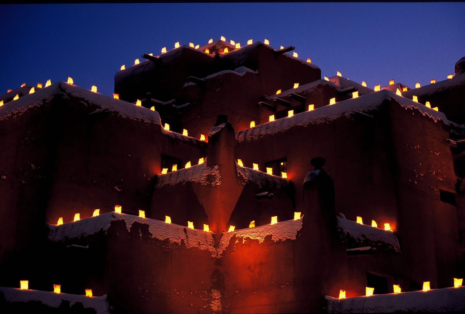Photos from the New Mexico Tourism Department
Farolitos, which are candles in paper bags, flicker in the night atop Santa Fe's Inn at Loretto. Farolito lanterns, also called luminarias, are a New Mexico holiday tradition.